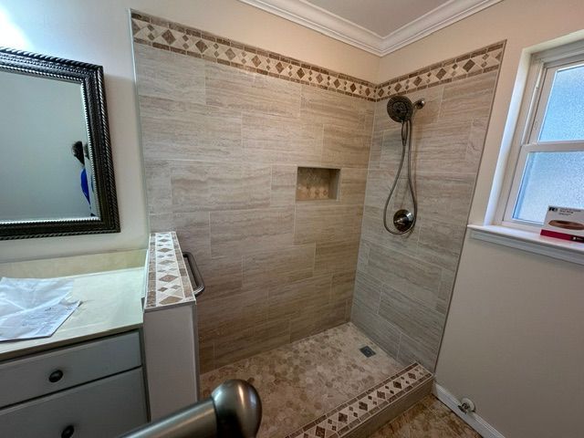 Bathroom shower with beige tile, a small niche, and a vanity beside it