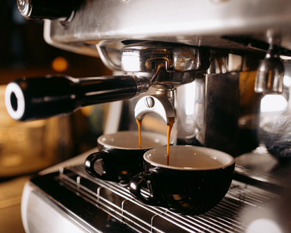 Macchina per caffè espresso che eroga il caffè in due tazze nere.