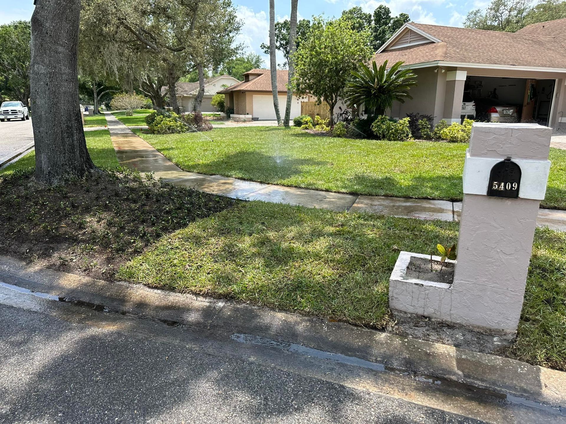 A mailbox is sitting on the side of the road in front of a house.