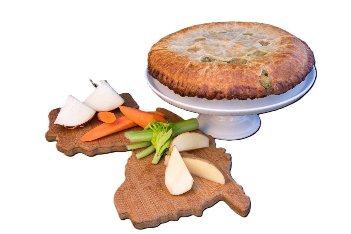 Savory pie on a cake stand with crudités on wooden boards.