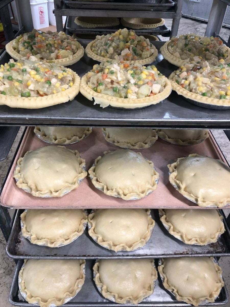 Nine chicken pot pies on a rack, three with filling, six covered in dough, ready to bake.