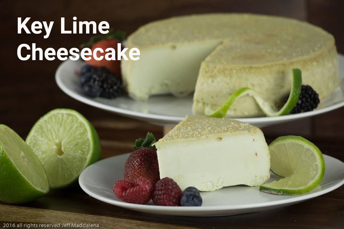 Key lime cheesecake with lime slices and berries on a white plate.