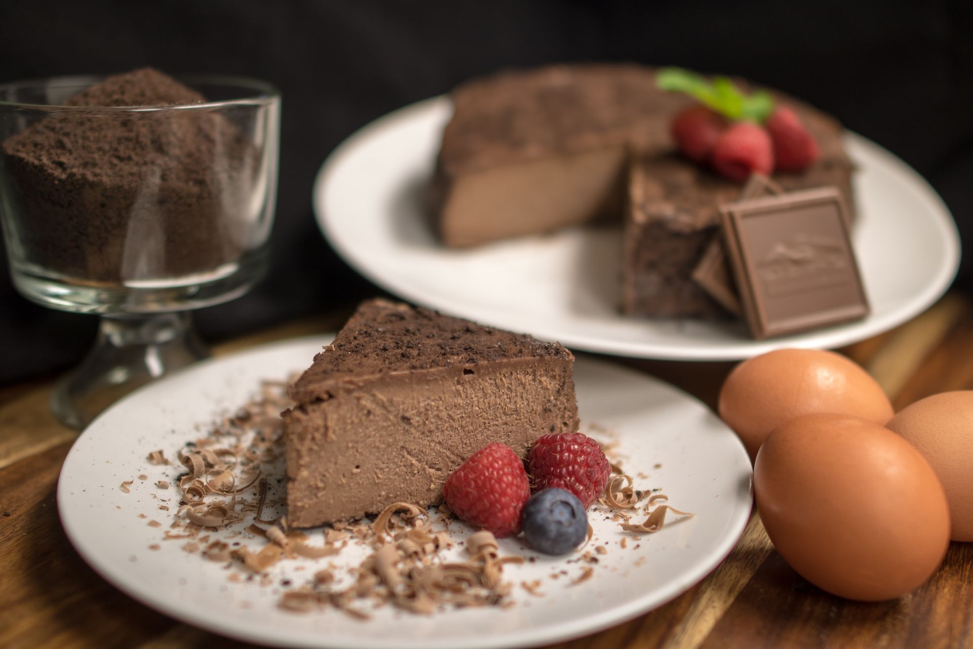 A white plate topped with a piece of chocolate cake and berries