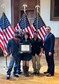 A group of people are posing for a picture in front of american flags.