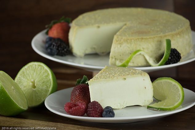 There is a piece of cake on a plate with berries and limes.