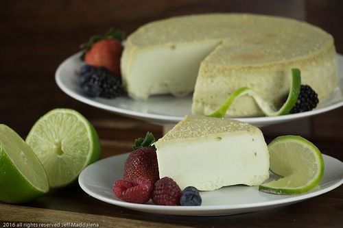 There is a piece of cake on a plate with berries and limes.