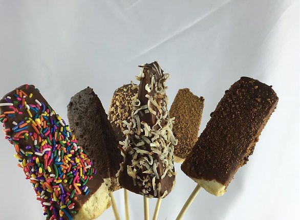 Chocolate-covered frozen treats on sticks, various toppings including sprinkles and coconut.