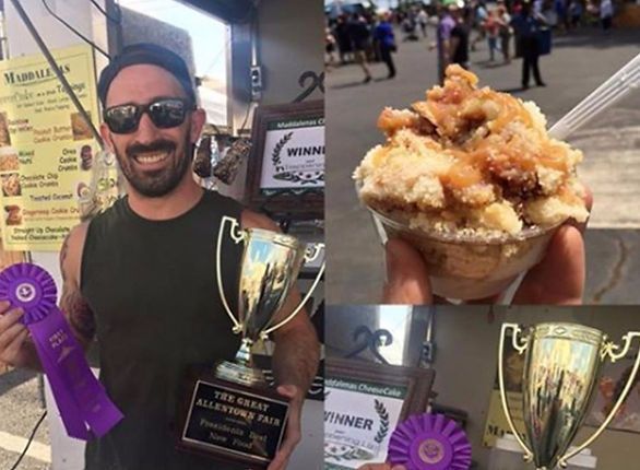 Man holding trophies and ribbons, smiling, at a fair. Apple crisp dessert in a cup.