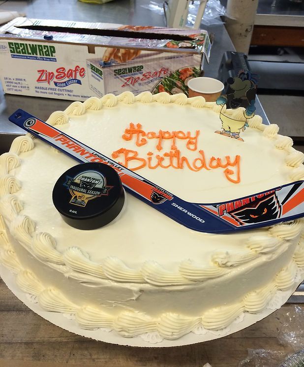A birthday cake with a hockey stick and puck on it