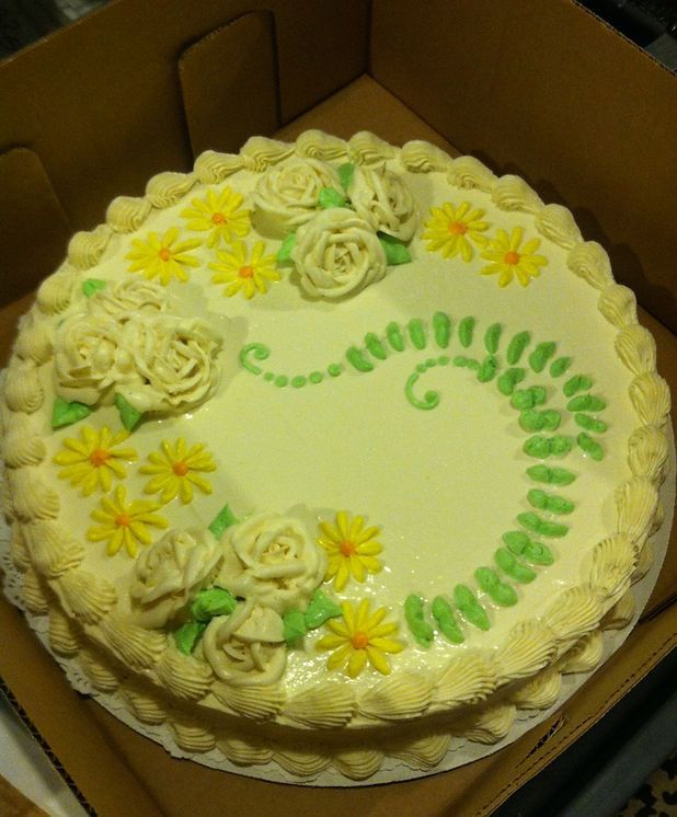 A cake with roses and daisies on it is in a box