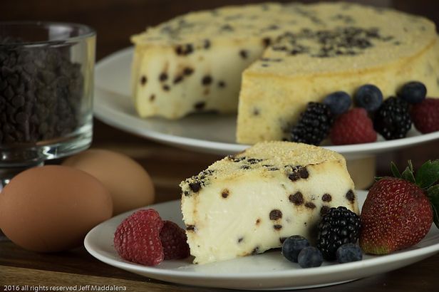 A slice of cheesecake with chocolate chips and berries on a plate