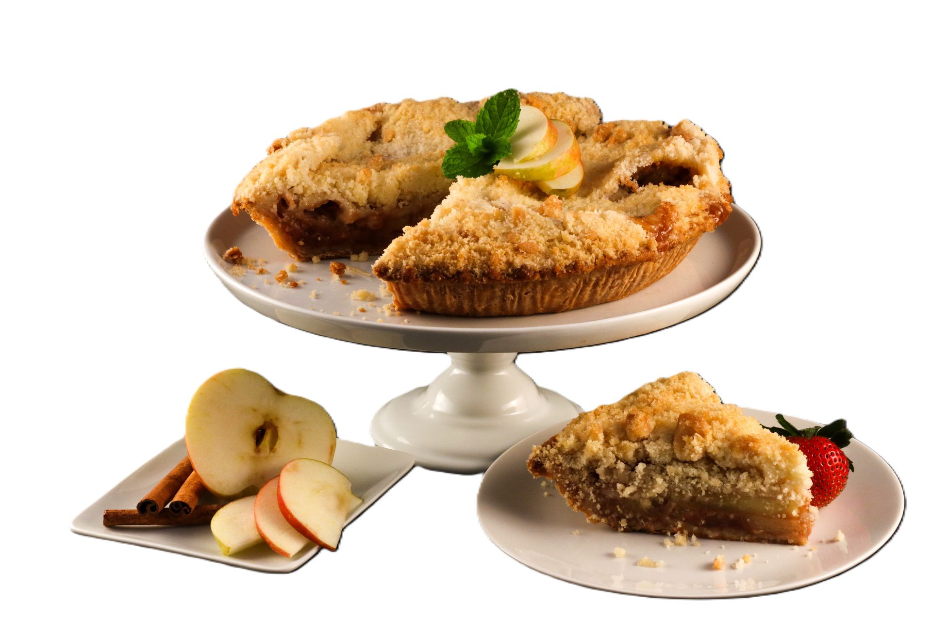 Apple crumble pie on a white pedestal, with apple slices, cinnamon, and a slice on a plate.