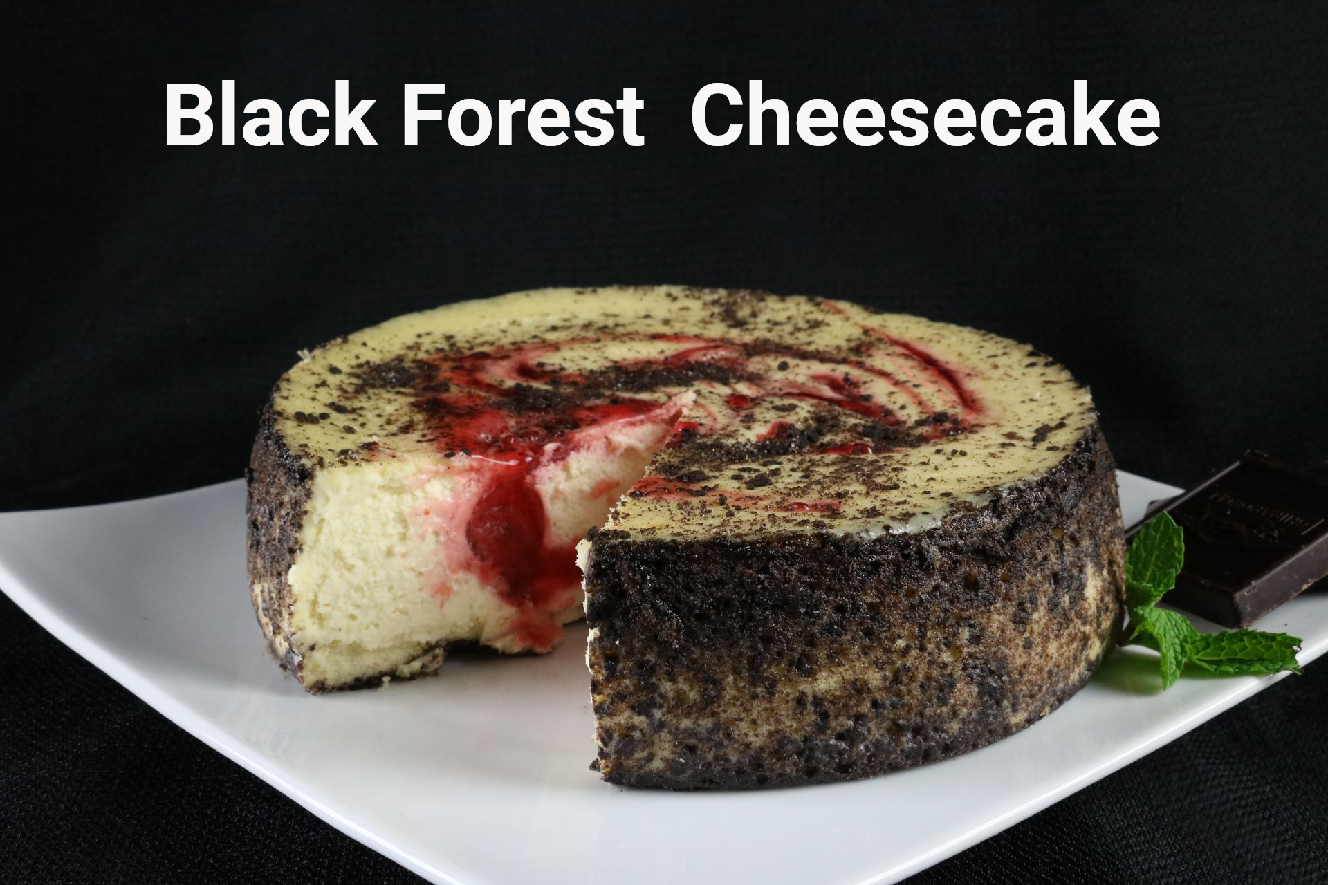 Black Forest cheesecake on a white plate, slice removed, dark chocolate and mint garnish.