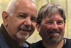 Two men are posing for a picture together and smiling for the camera.