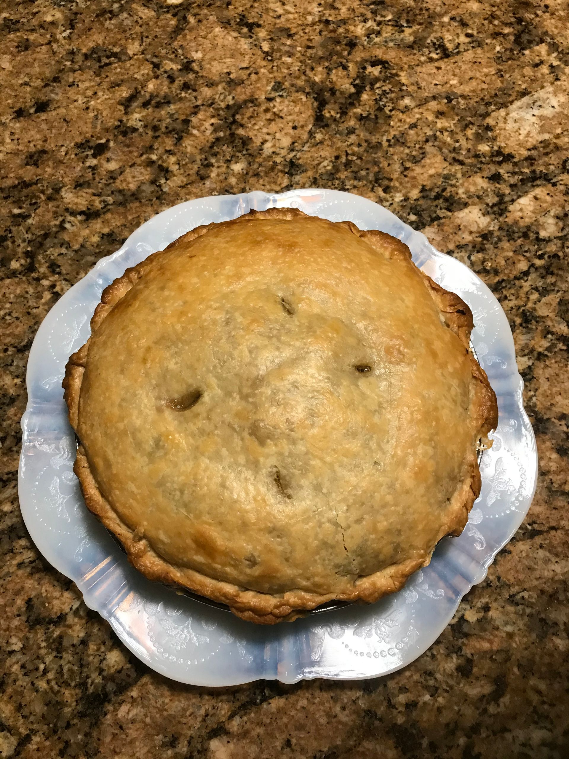 Baked pie on a scalloped blue-tinted plate, golden-brown crust.