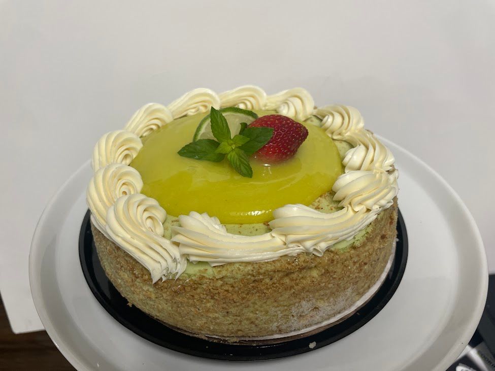 A lemon cheesecake with a strawberry on top is on a white plate.