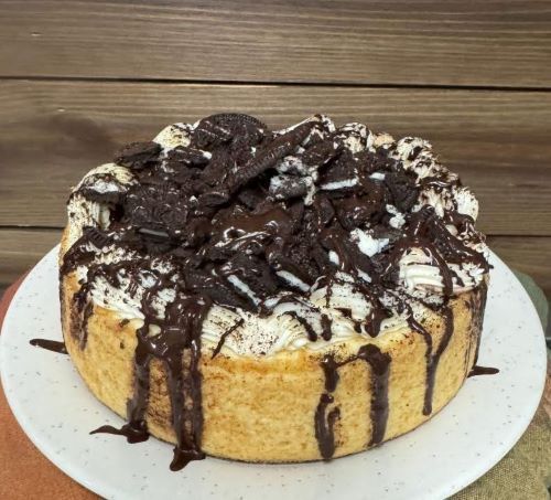 A cheesecake with chocolate sauce and oreos on top