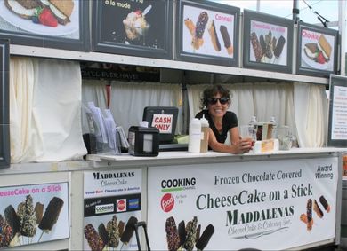 A woman behind a counter selling cheesecake on a stick