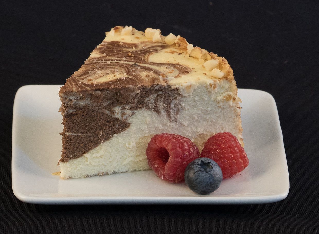 A slice of cheesecake with raspberries and blueberries on a white plate