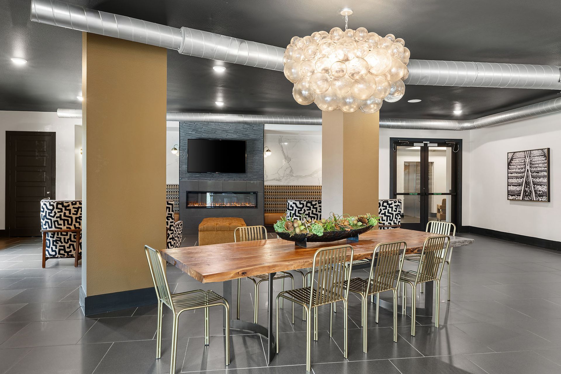 Modern dining room with a long table, clear chairs, and a large chandelier under a curved ceiling at Two99 Monroe.