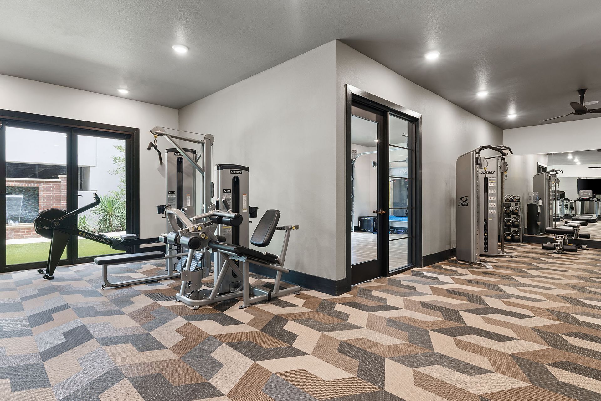 Modern gym with exercise machines, patterned carpet, and large windows overlooking outdoors at Two99 Monroe.
