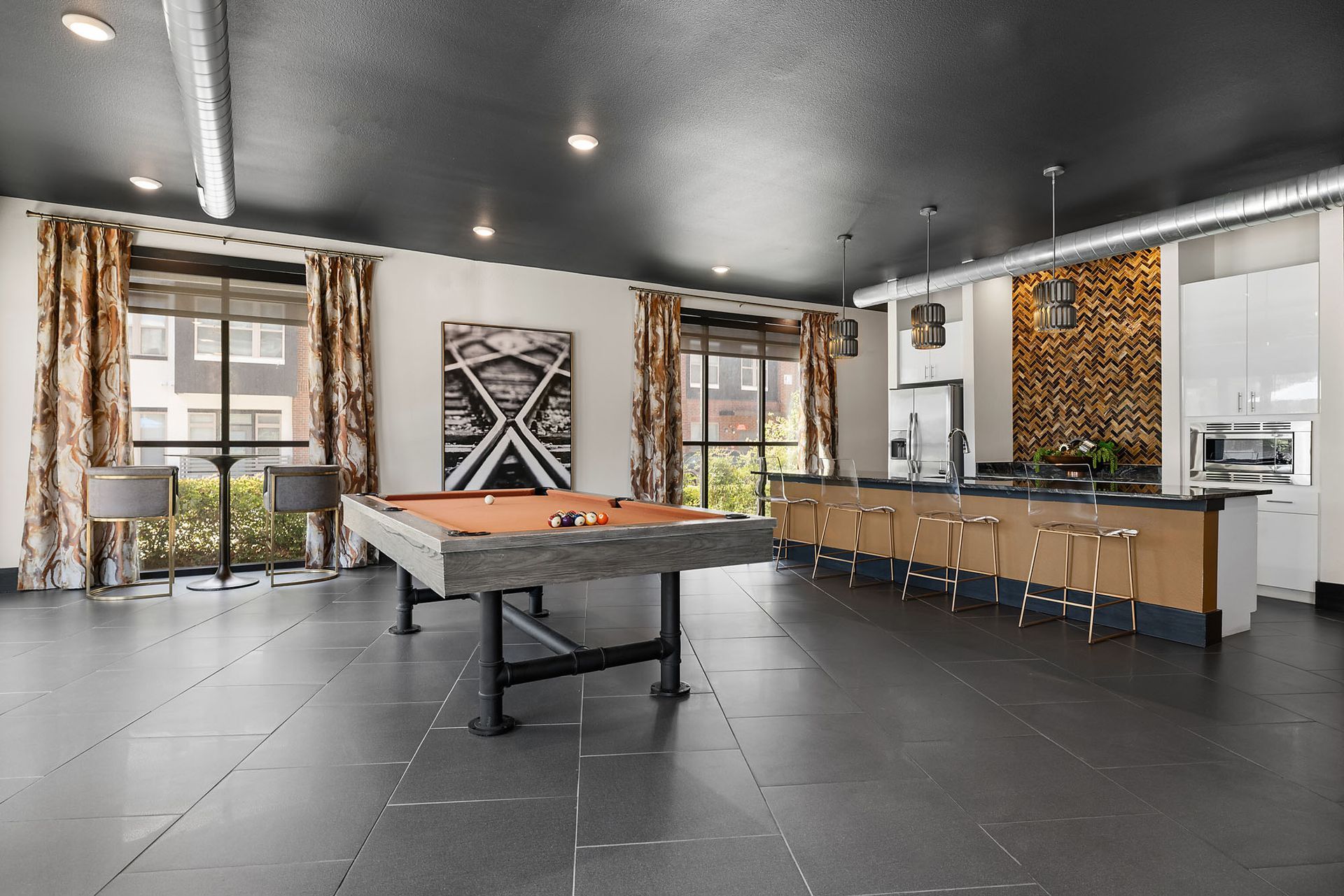 Modern game room with pool table, bar counter, and large windows at Two99 Monroe
