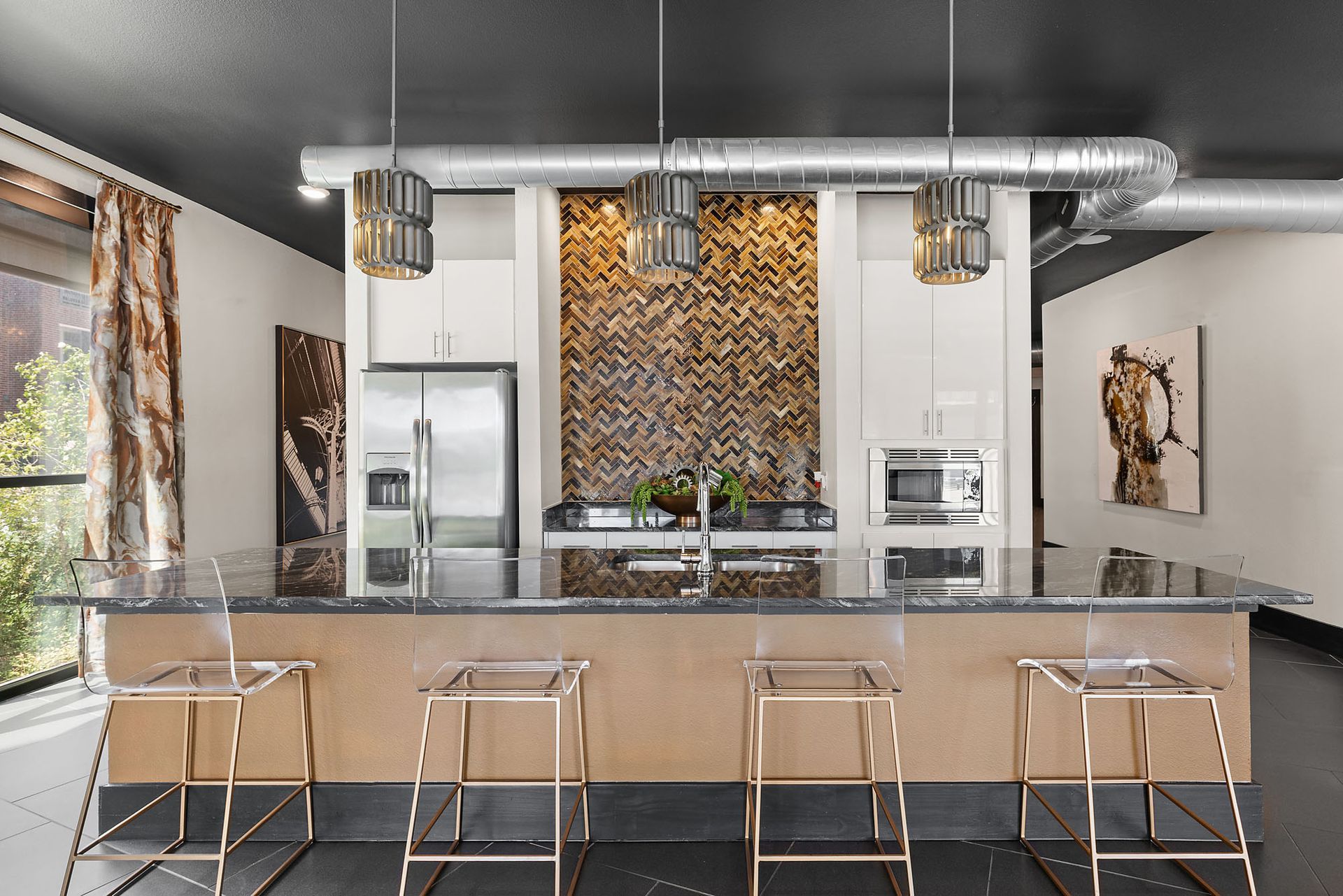 Modern kitchen with a large island, bar stools, stainless appliances, and exposed ductwork at Two99 Monroe