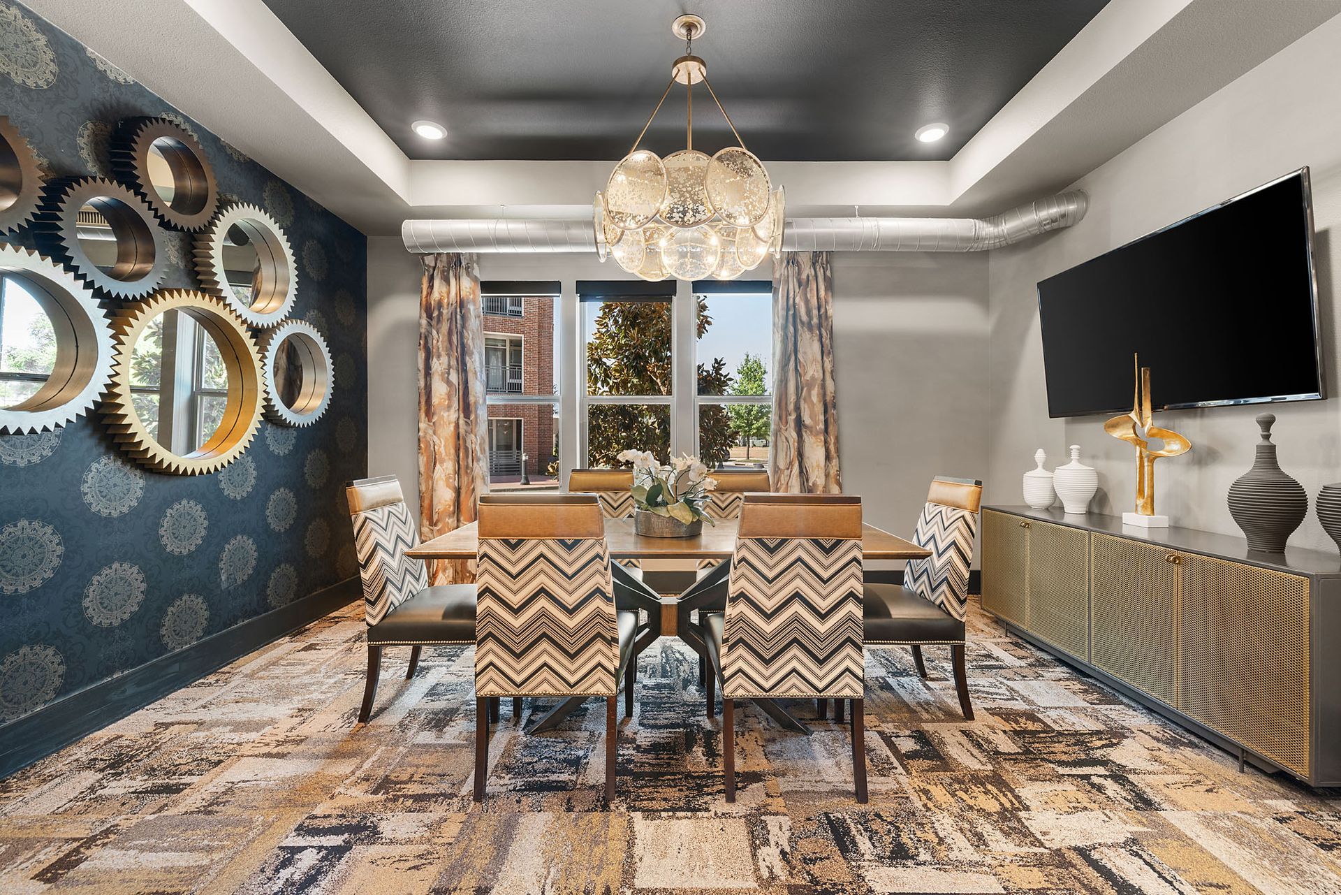Elegant dining room with six patterned chairs, crystal chandelier, wall mirrors, and large window at Two99 Monroe.