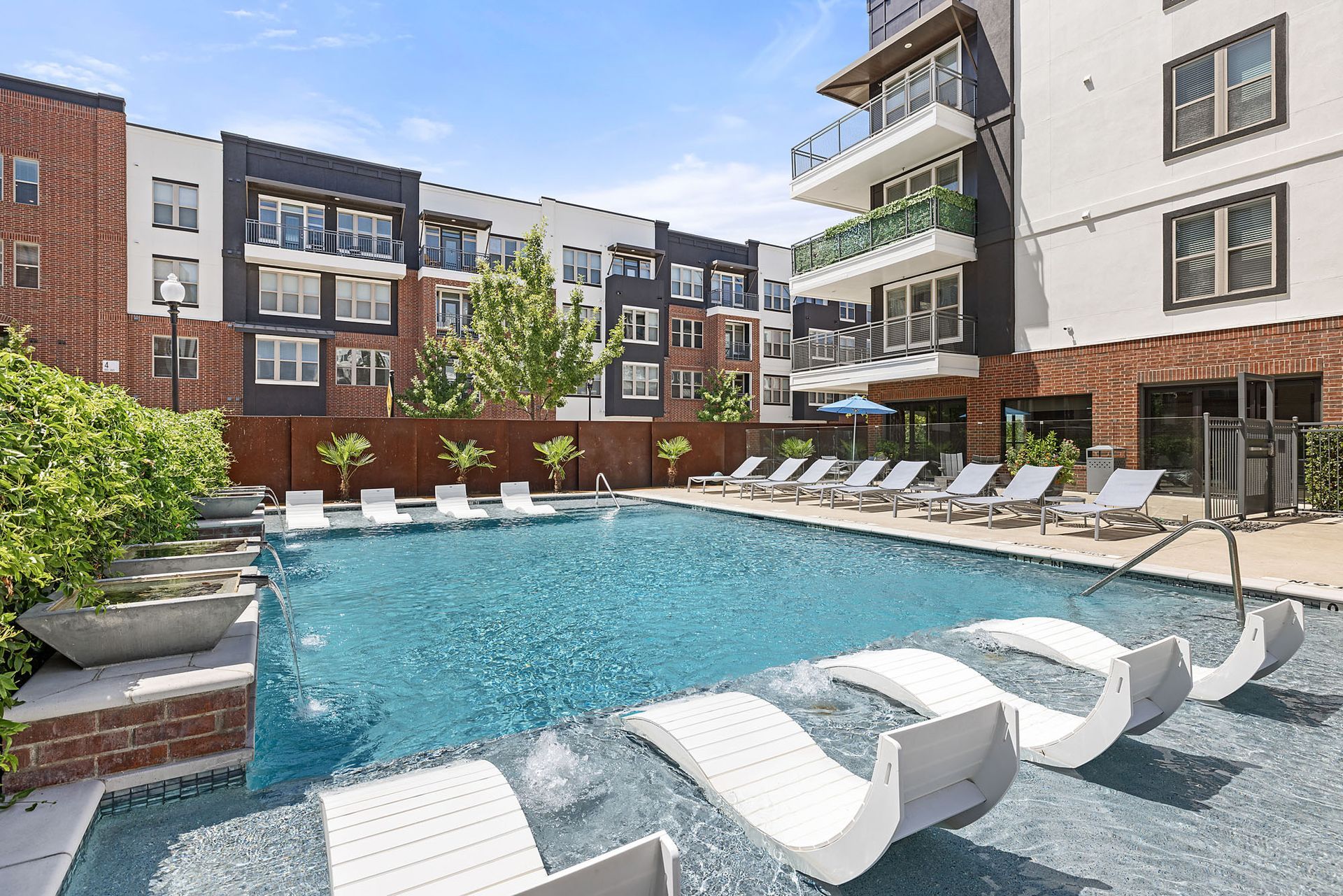 Modern apartment courtyard with a swimming pool, lounge chairs, and surrounding balconies at Two99 Monroe.