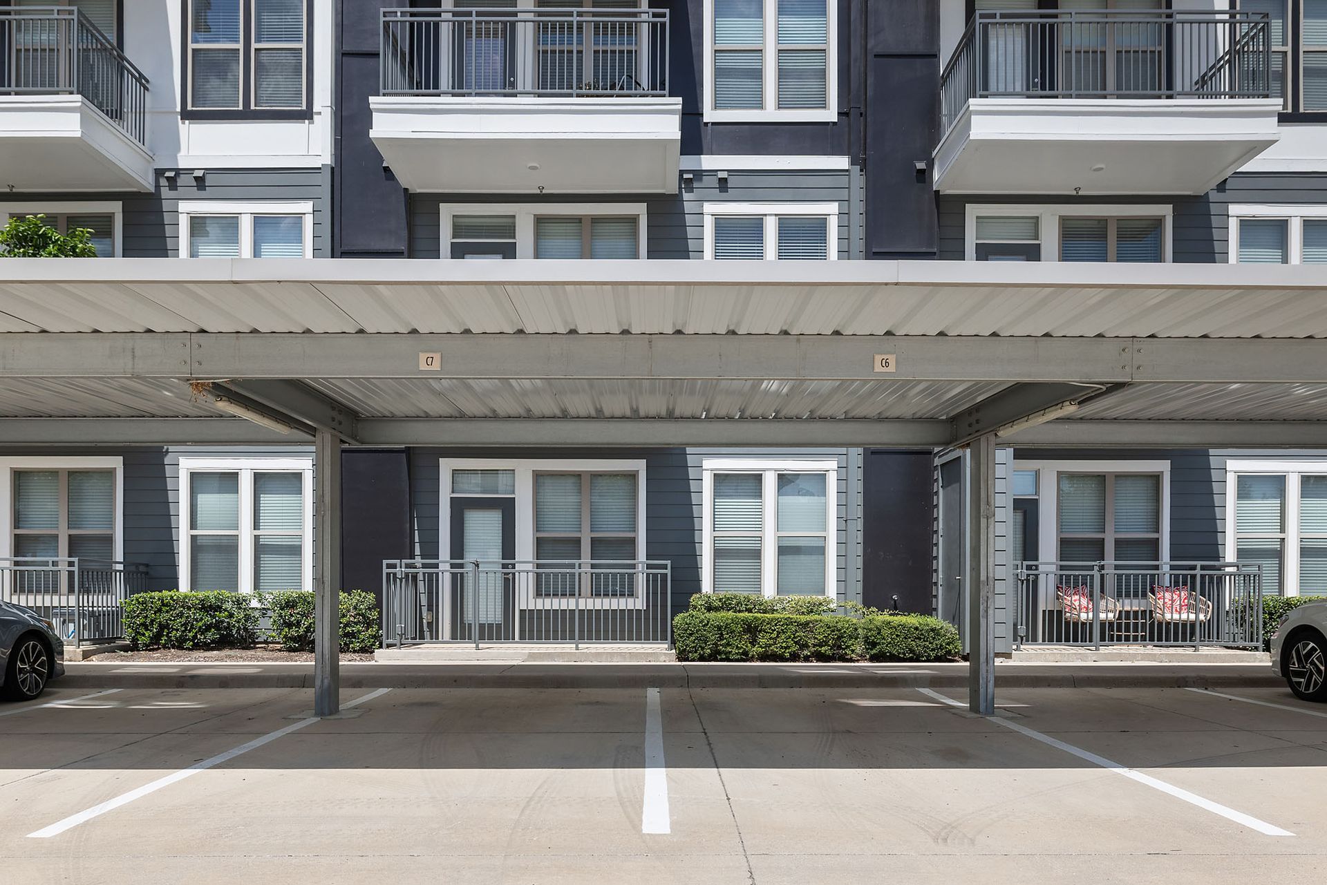 Apartment building parking area with covered spaces and balconies above at Two99 Monroe.