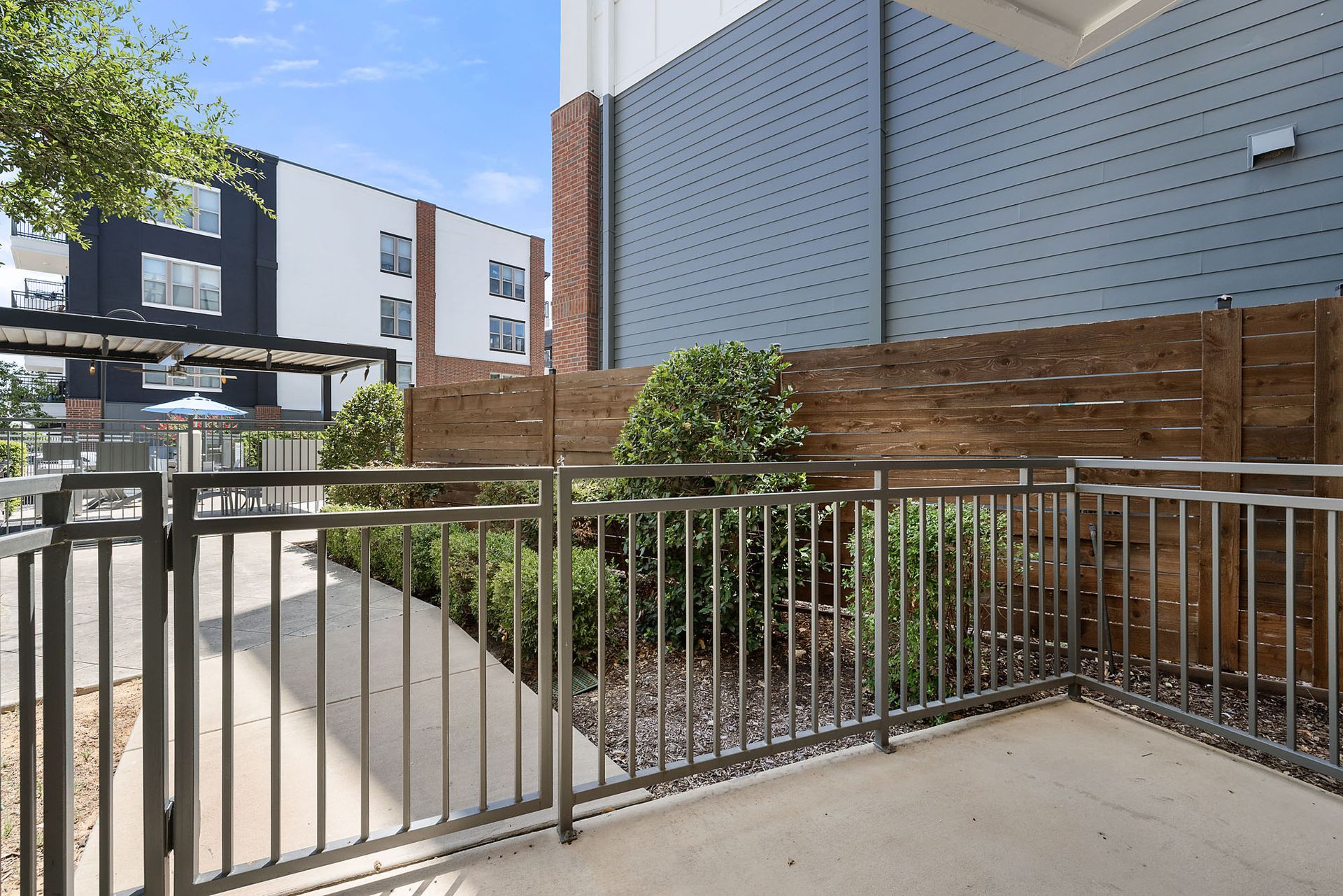 Modern building courtyard with metal railing, concrete path, and landscaped planter in sunlight at Two99 Monroe.