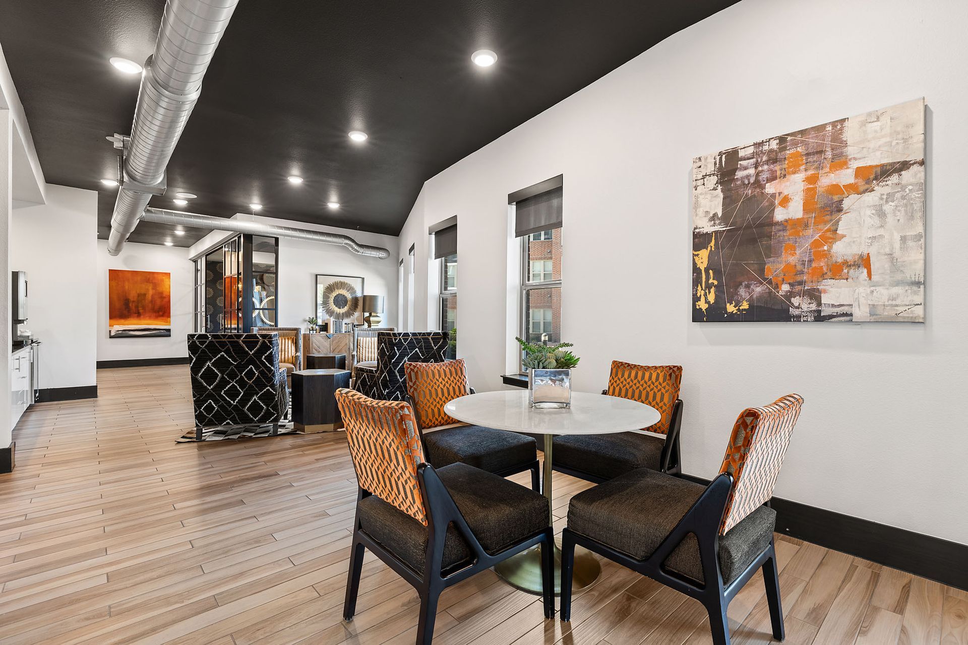 Modern office lounge with tables, patterned chairs, white walls, and abstract wall art at Two99 Monroe