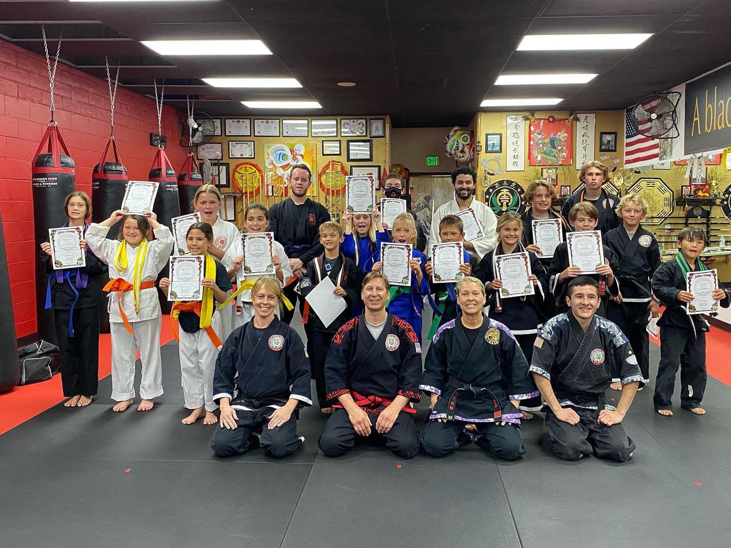 A group of people in karate uniforms are posing for a picture in a gym.
