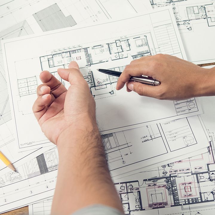 Une personne regarde le plan d'un bâtiment avec un stylo.