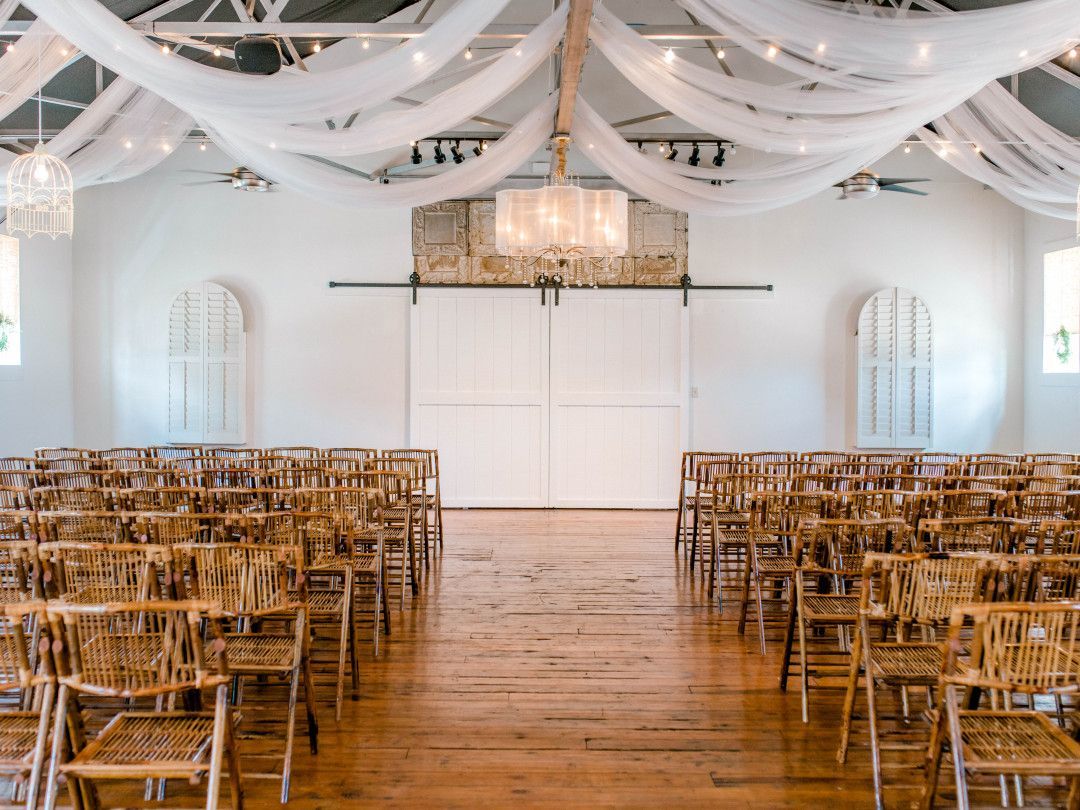 A large room filled with wooden chairs and white sheets hanging from the ceiling.