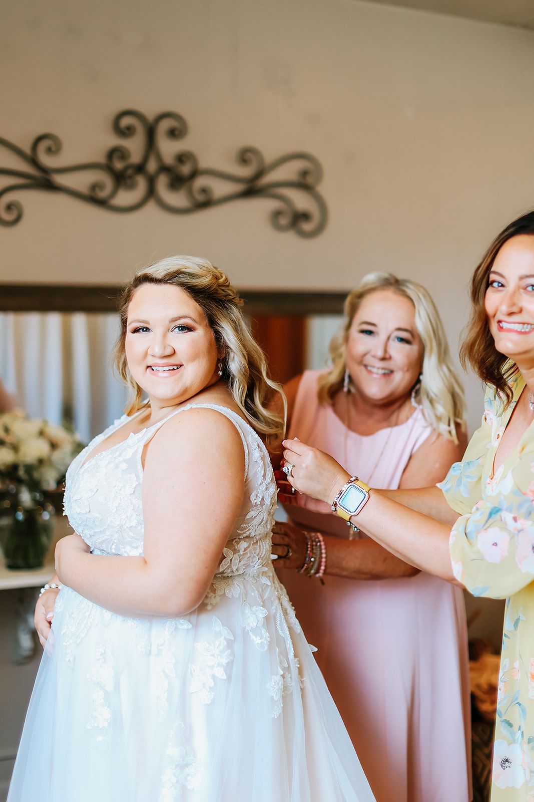 A bride is getting ready for her wedding with two women.