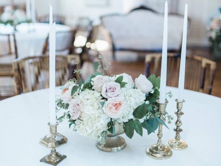 A table with a vase of flowers and candles on it.