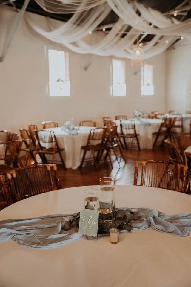 A room with tables and chairs set up for a wedding reception.