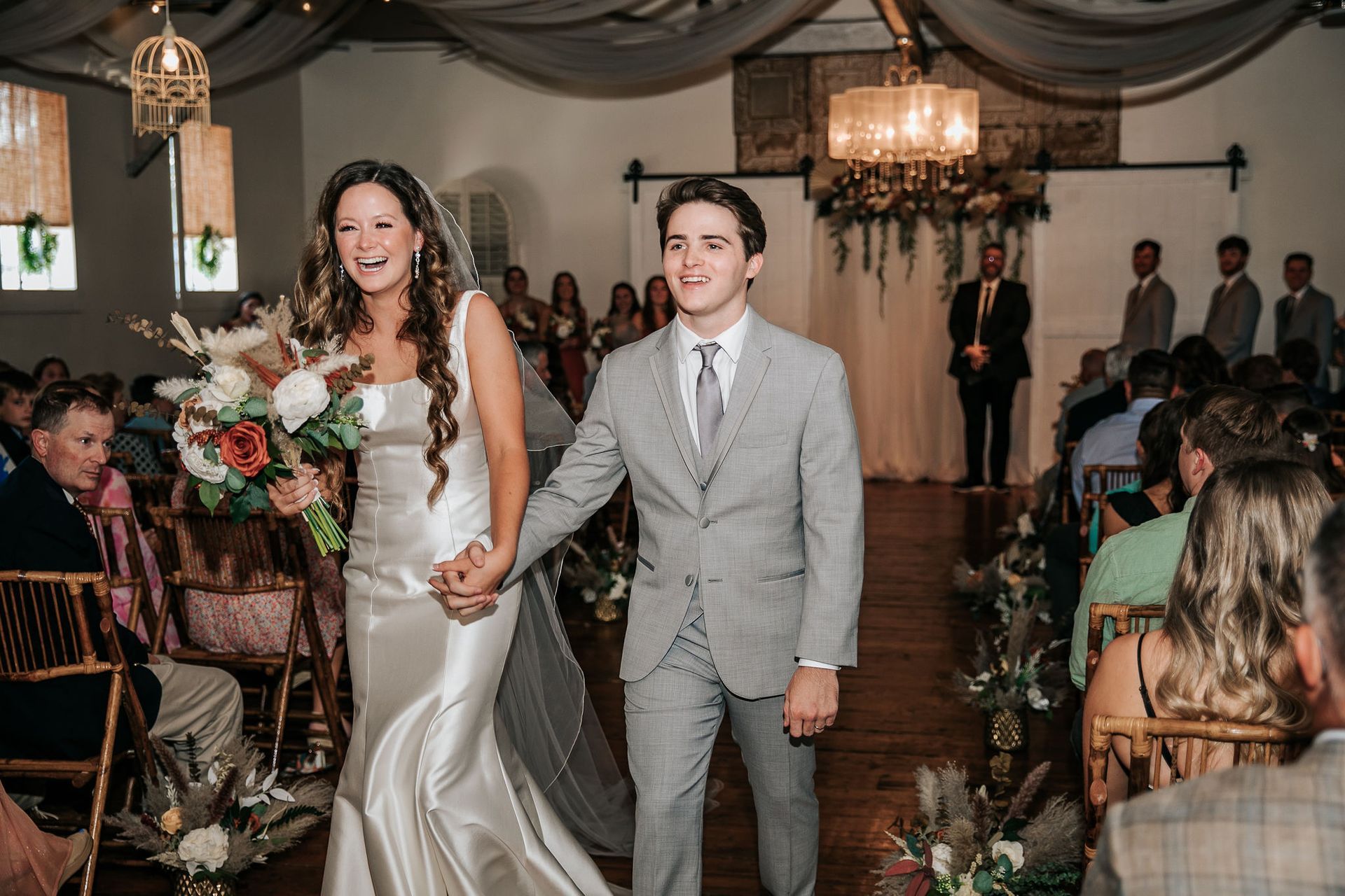 A bride and groom are walking down the aisle at their wedding holding hands.