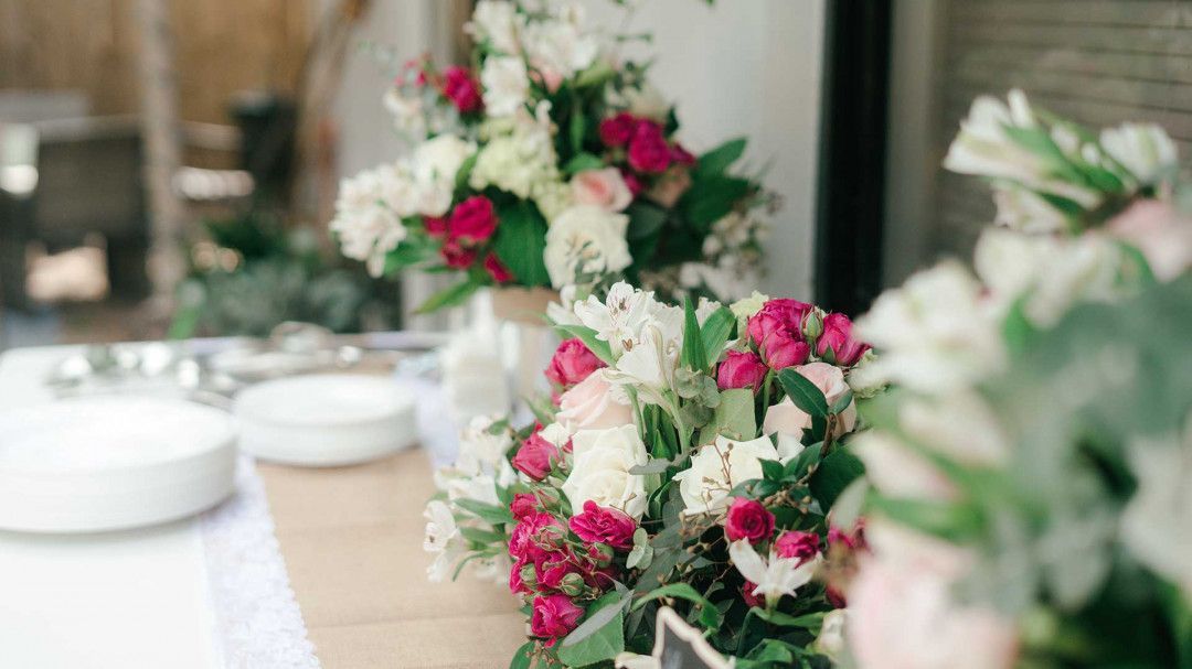 A table decorated with pink and white flowers and plates.