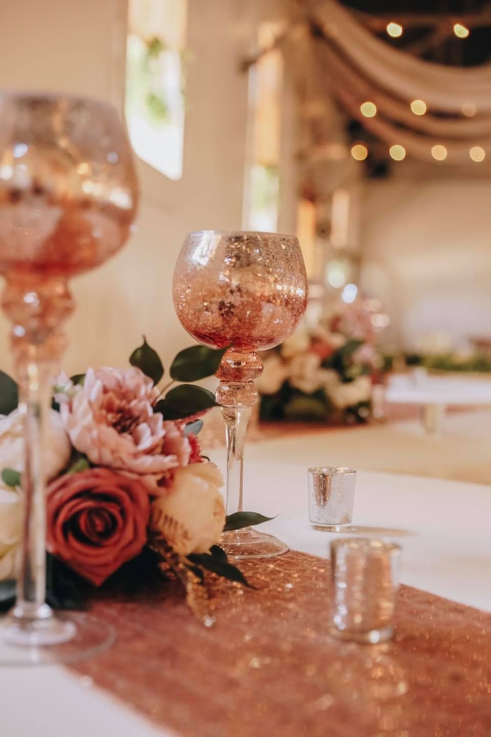 A couple of wine glasses sitting on top of a table with flowers and candles.