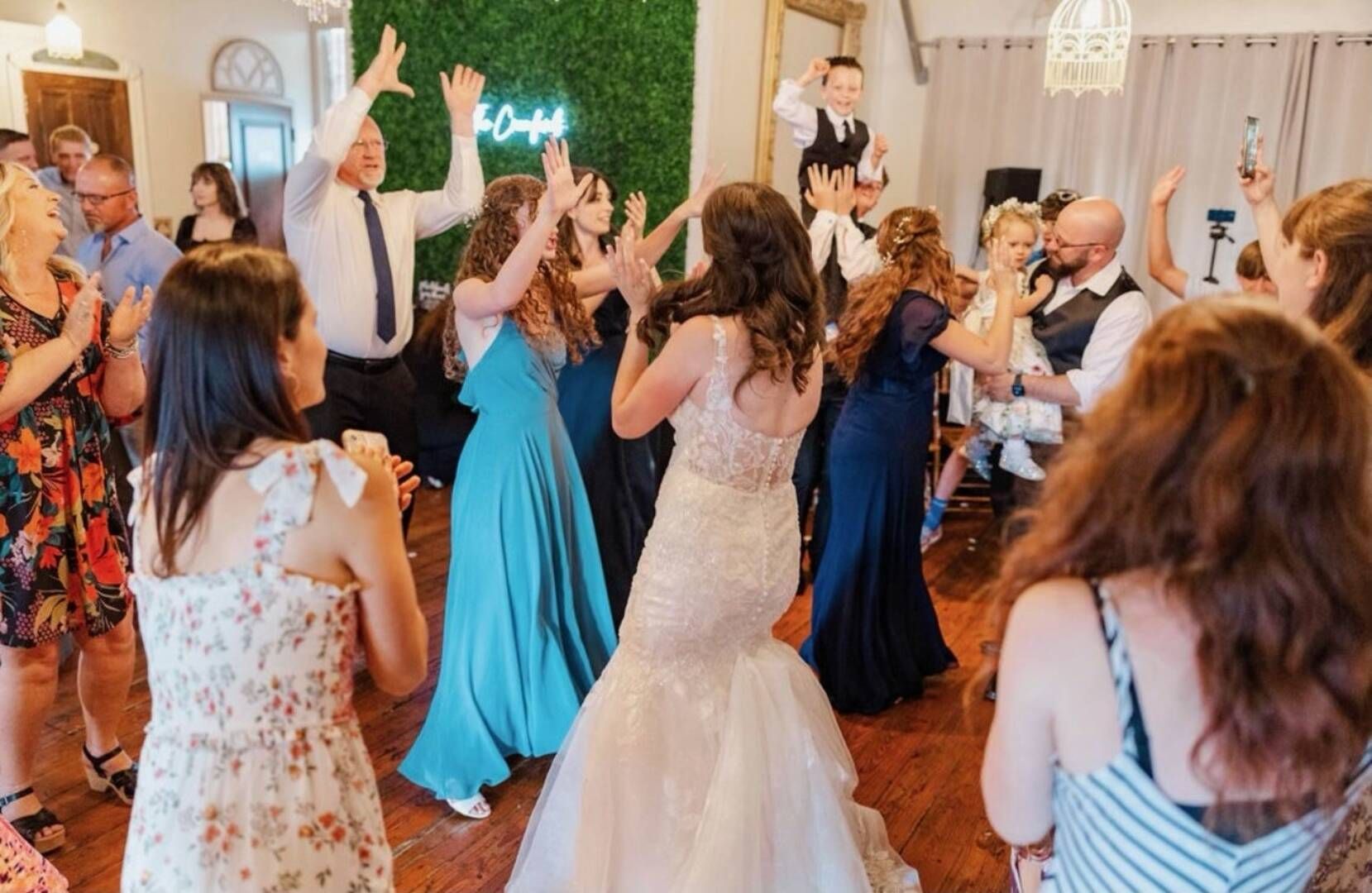 A group of people are dancing at a wedding reception.