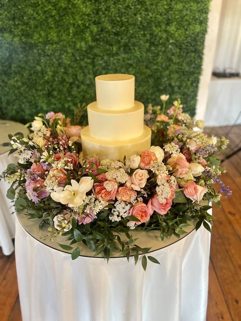 A wedding cake is sitting on top of a table surrounded by flowers.