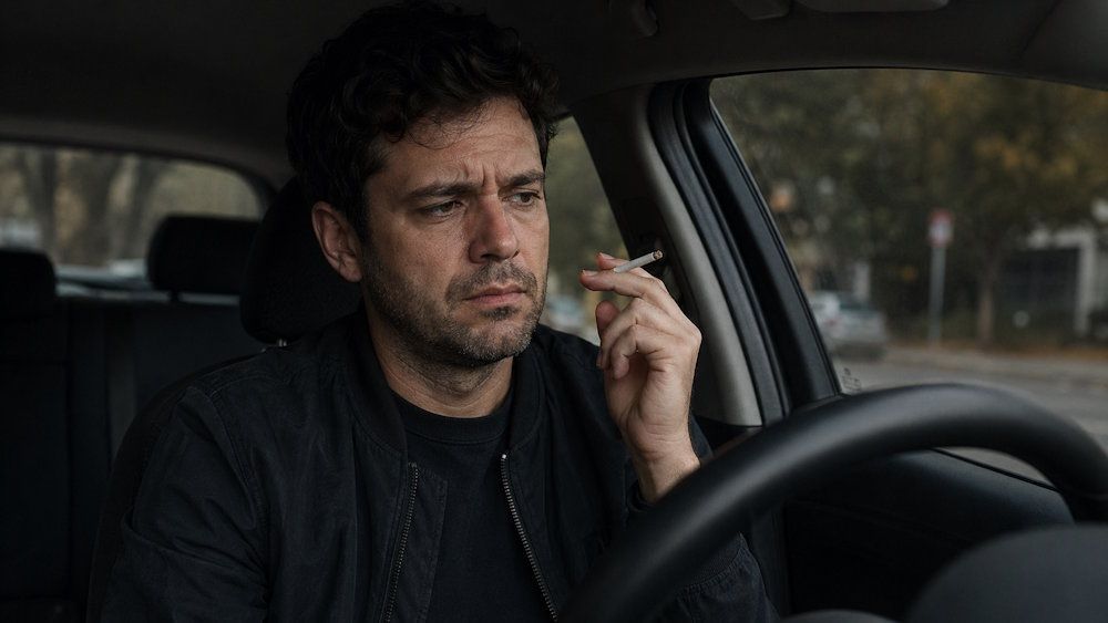 Man sitting in his car holding a cigarette, wanting to quit but disgusted because he can't quit