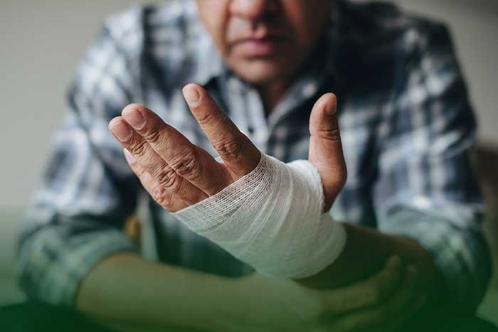 A man with a bandaged hand is sitting at a table.
