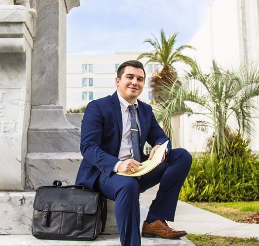 A man in a suit and tie is sitting on steps with a briefcase