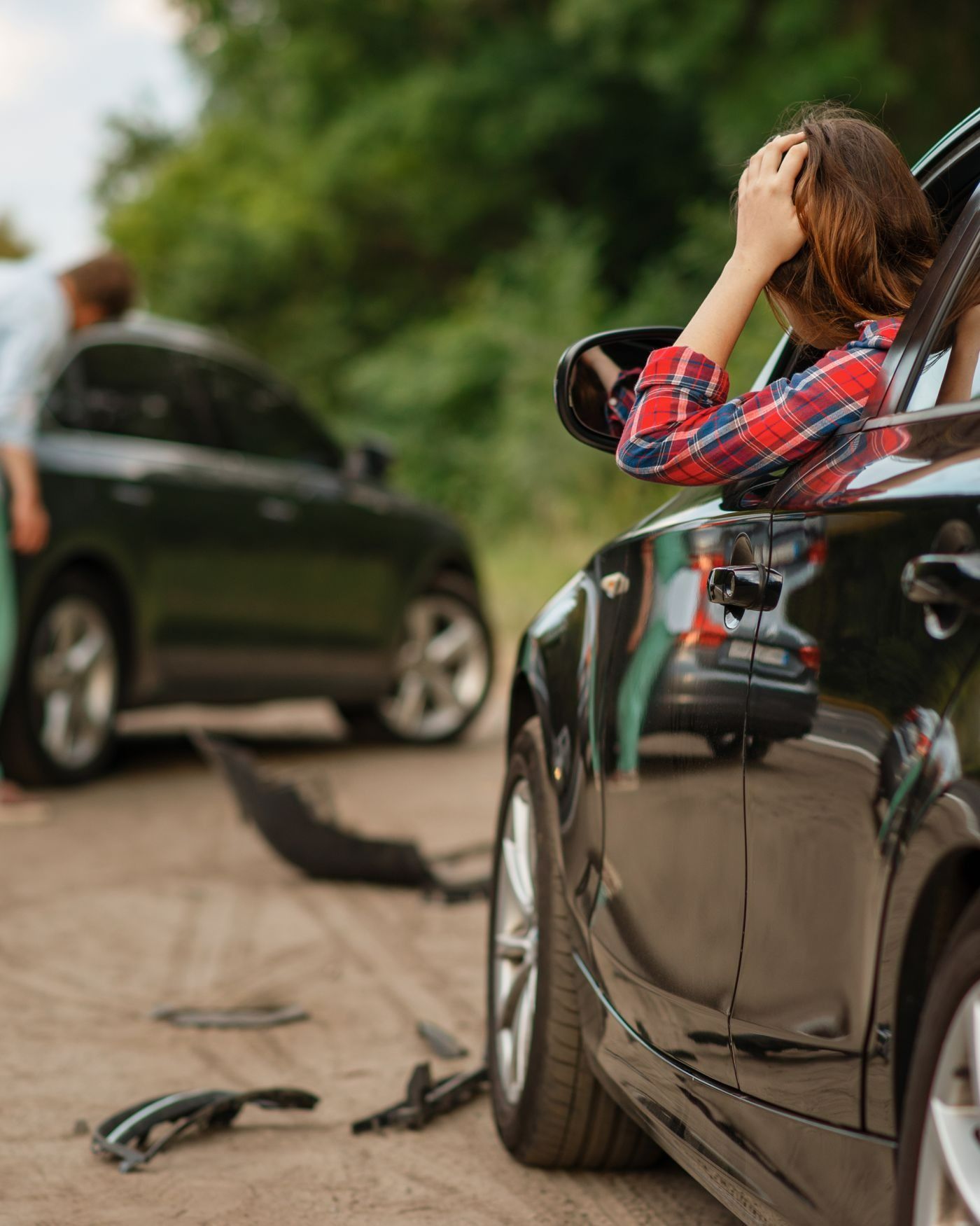 A woman is sitting in a car with her head in her hands.