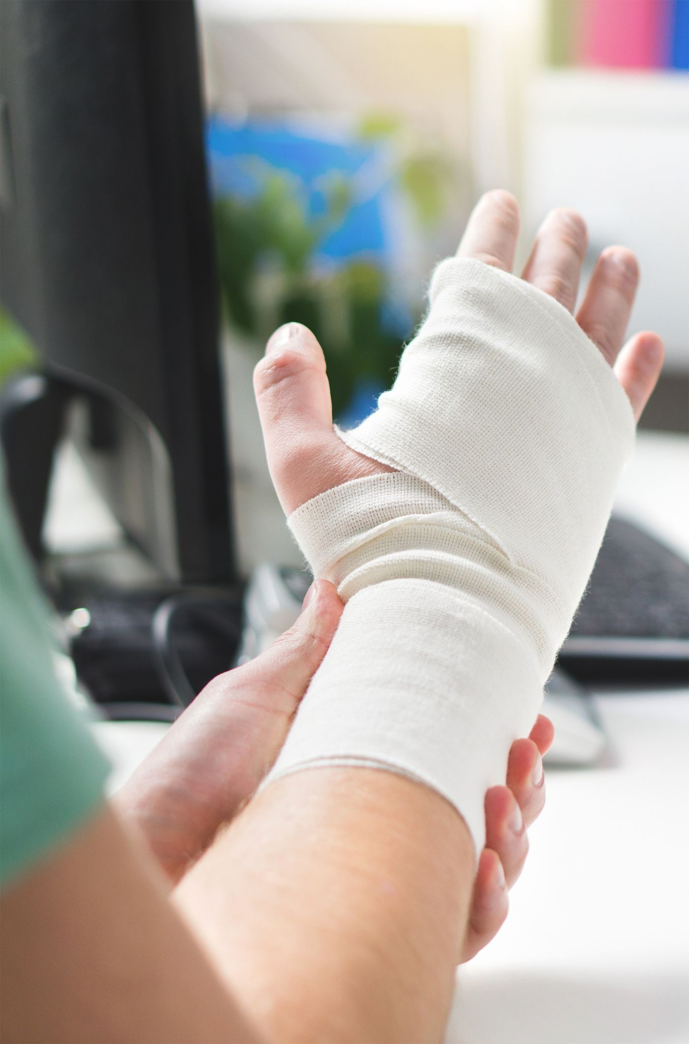 A person is wrapping their hand in a bandage.