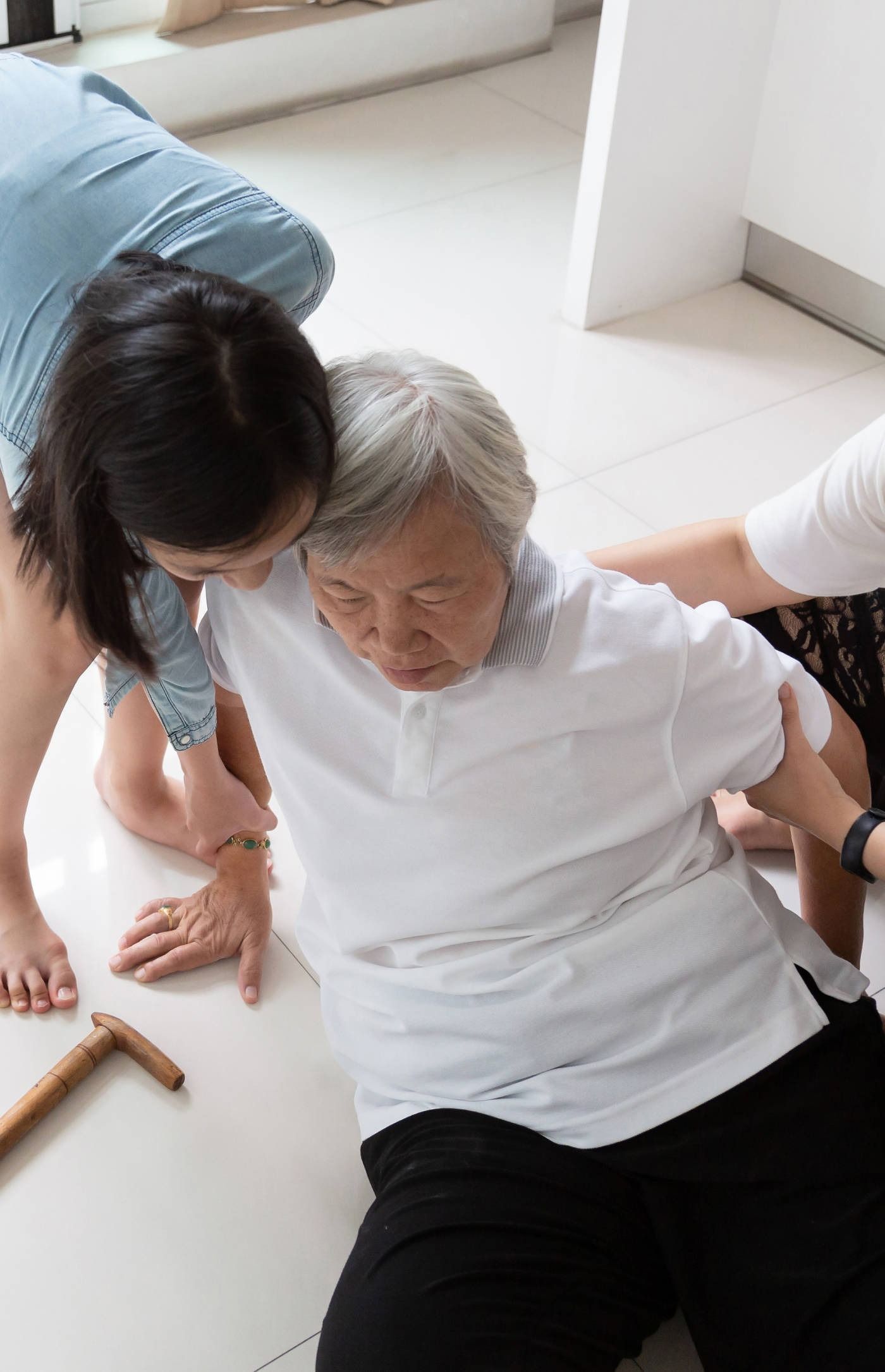 A woman is helping an elderly woman who has fallen on the floor.
