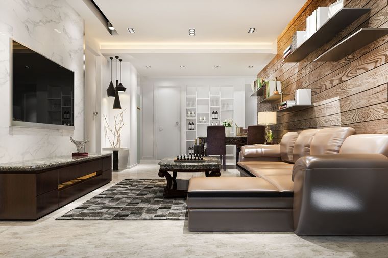Modern living room with beige sectional sofa, wall-mounted TV, marble accents, and patterned rug